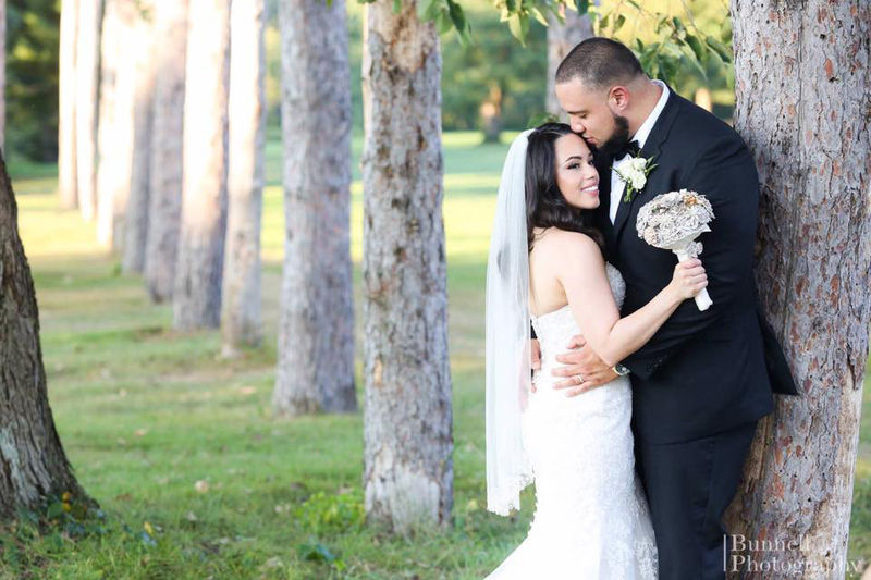 Bride and groom standing by tree